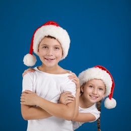 Happy little children in Santa hats on blue background. Christmas celebration Image of Happy little children in Santa hats on blue background. Christmas celebration