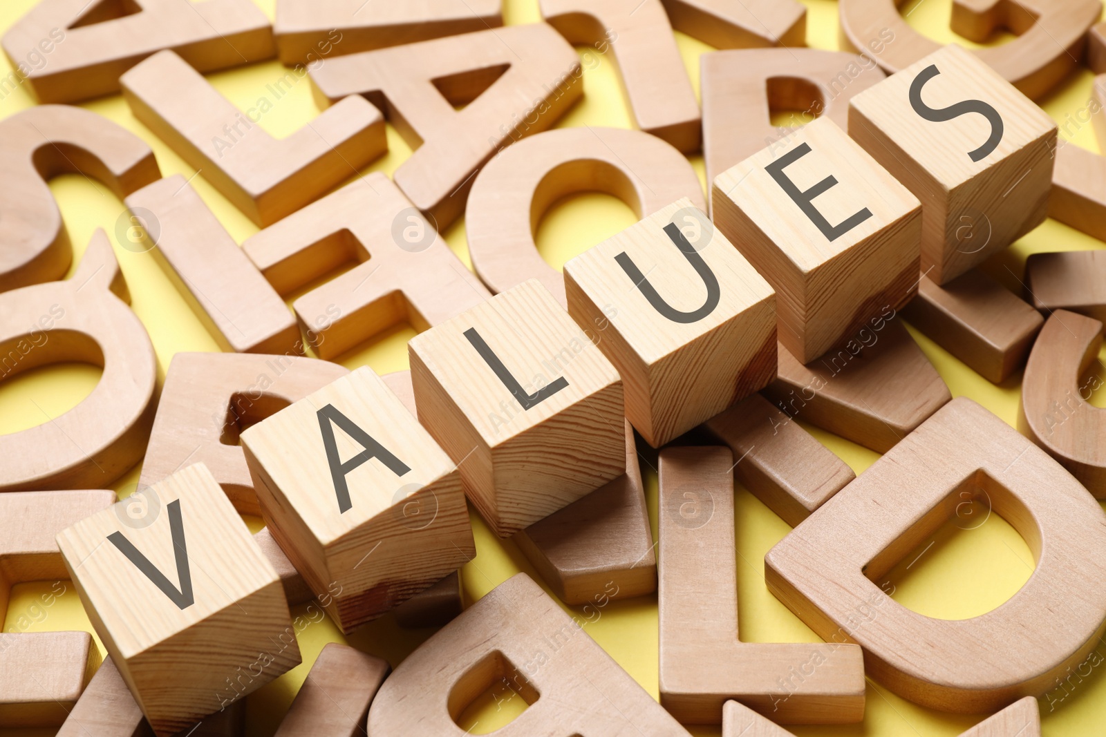 Cubes with word VALUES and wooden letters on yellow background Photo of Cubes with word VALUES and wooden letters on yellow background