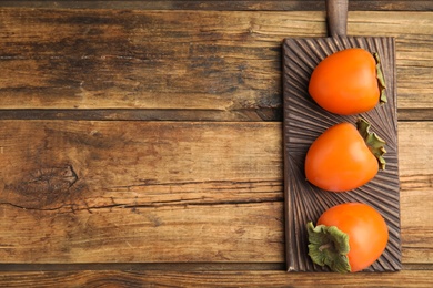 Tasty ripe persimmons on wooden table, top view. Space for text Photo of Tasty ripe persimmons on wooden table, top view. Space for text