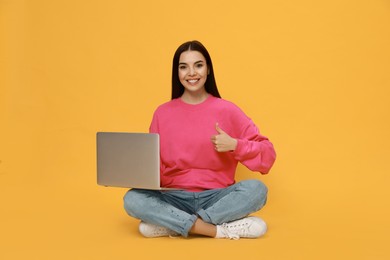 Young woman with modern laptop on yellow background Photo of Young woman with modern laptop on yellow background