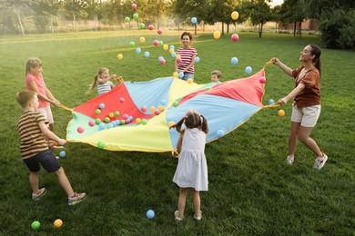 Group of children and teachers playing with rainbow playground parachute on green grass. Summer camp activity Photo of Group of children and teachers playing with rainbow playground parachute on green grass. Summer camp activity