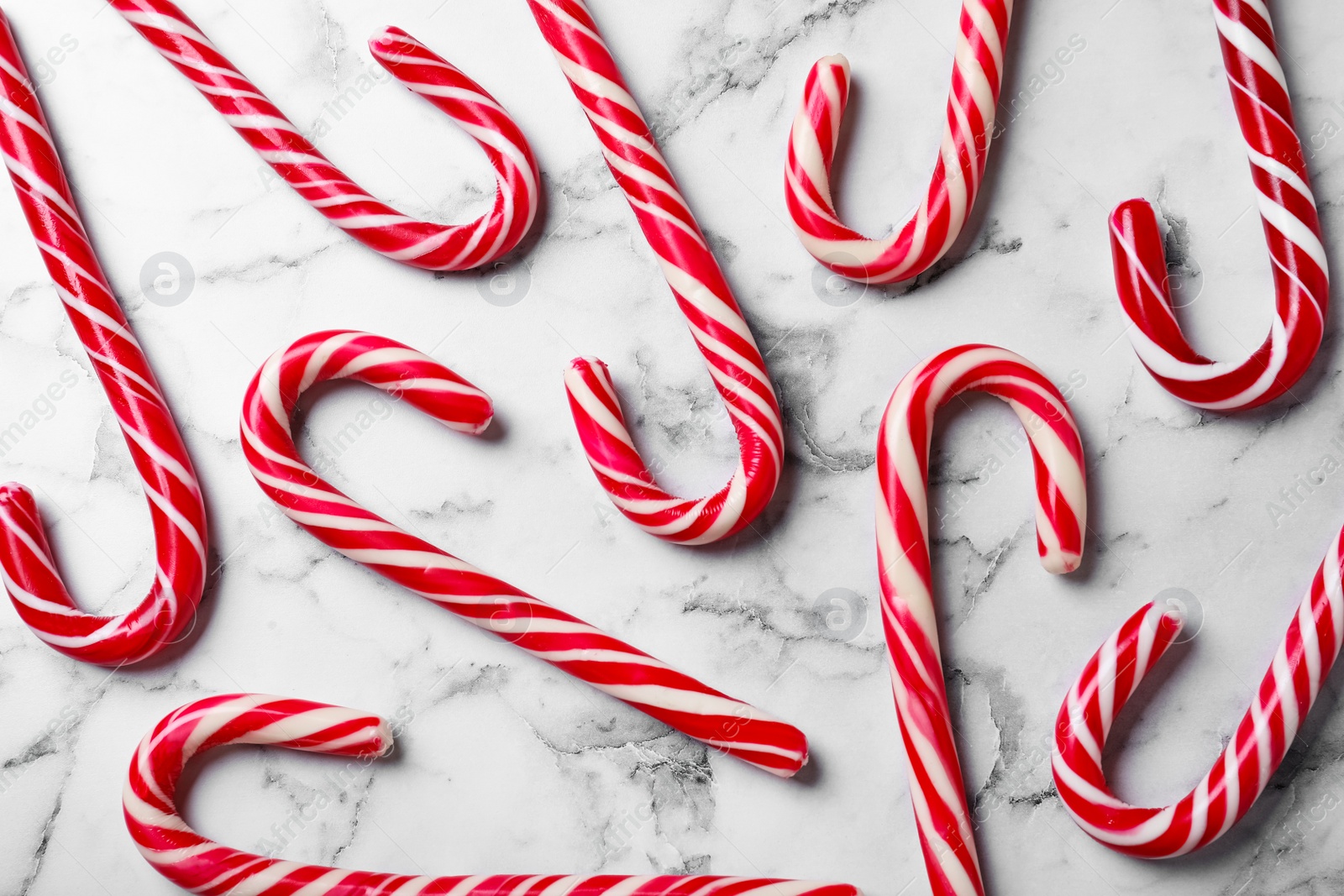 Sweet Christmas candy canes on white marble background, flat lay Photo of Sweet Christmas candy canes on white marble background, flat lay