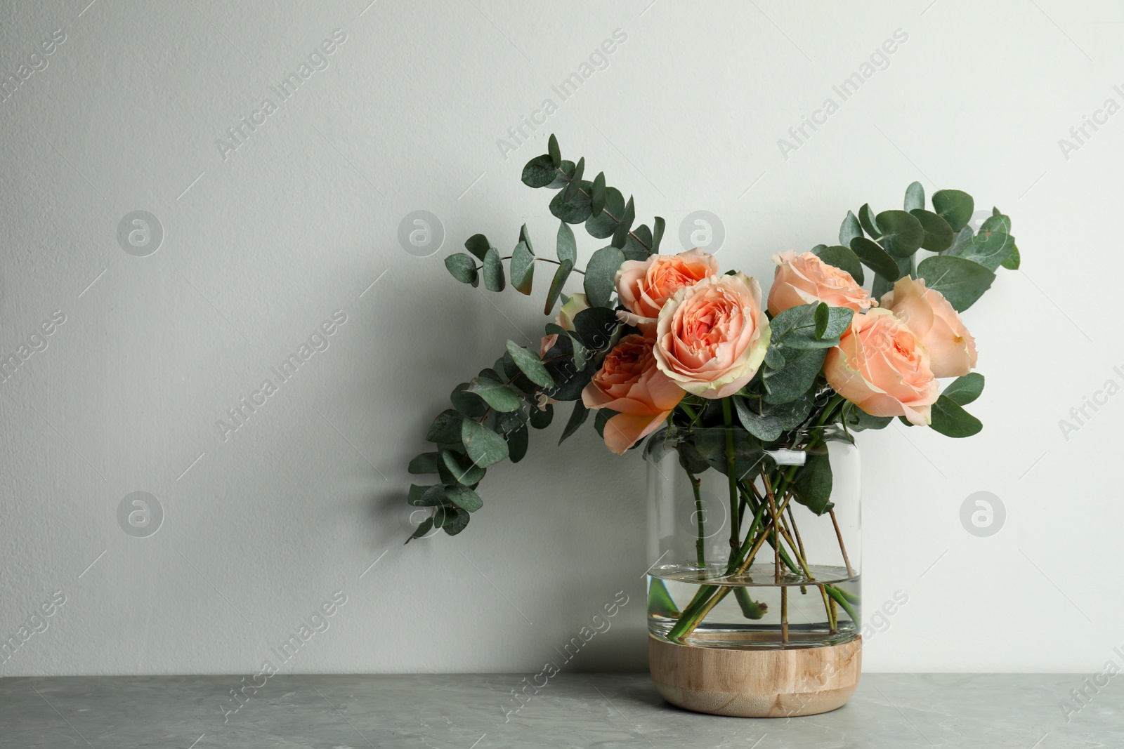 Bouquet of beautiful flowers in glass vase on grey table against white background. Space for text Photo of Bouquet of beautiful flowers in glass vase on grey table against white background. Space for text