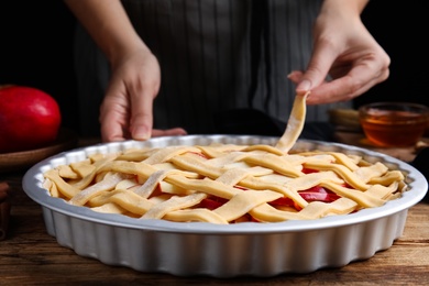 Woman making lattice top for traditional English apple pie at wooden table, closeup Photo of Woman making lattice top for traditional English apple pie at wooden table, closeup