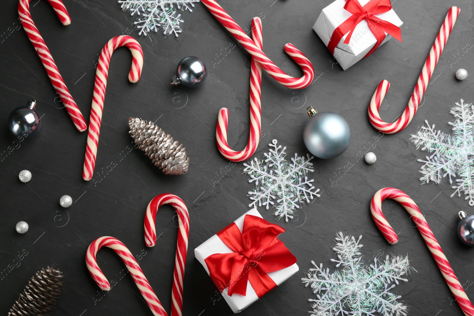 Photo of Flat lay composition with candy canes and Christmas decor on black table