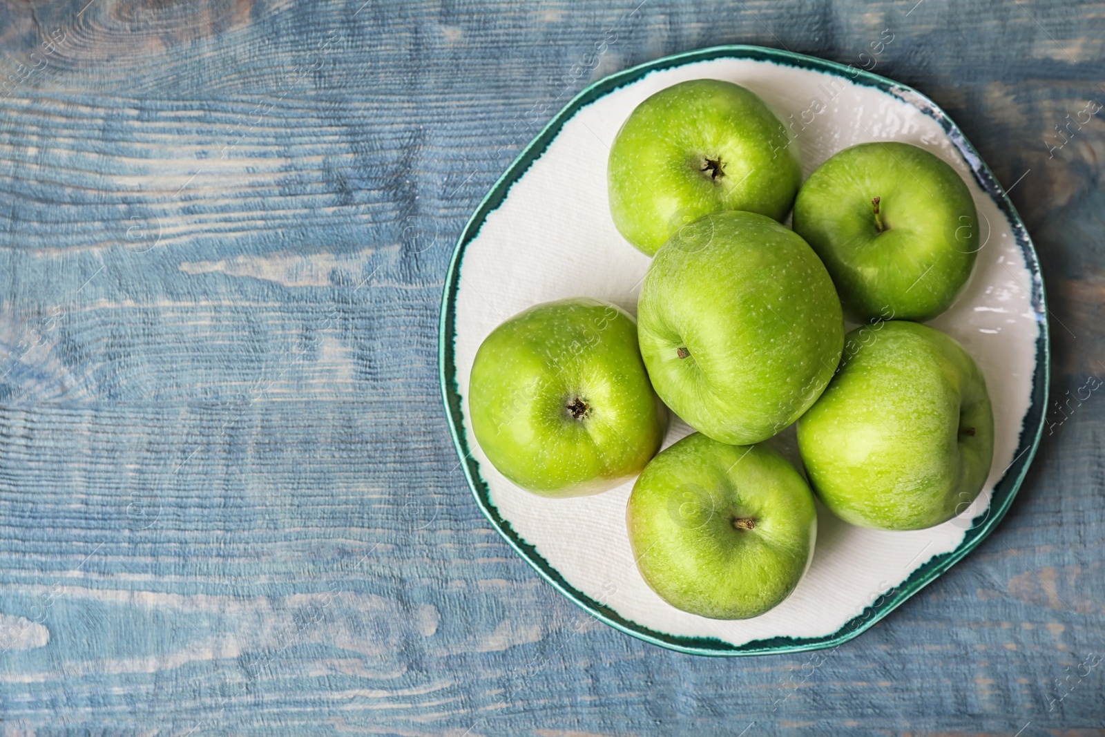 Plate with fresh green apples on wooden background, top view Photo of Plate with fresh green apples on wooden background, top view