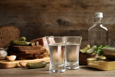 Cold Russian vodka with snacks on wooden table Photo of Cold Russian vodka with snacks on wooden table