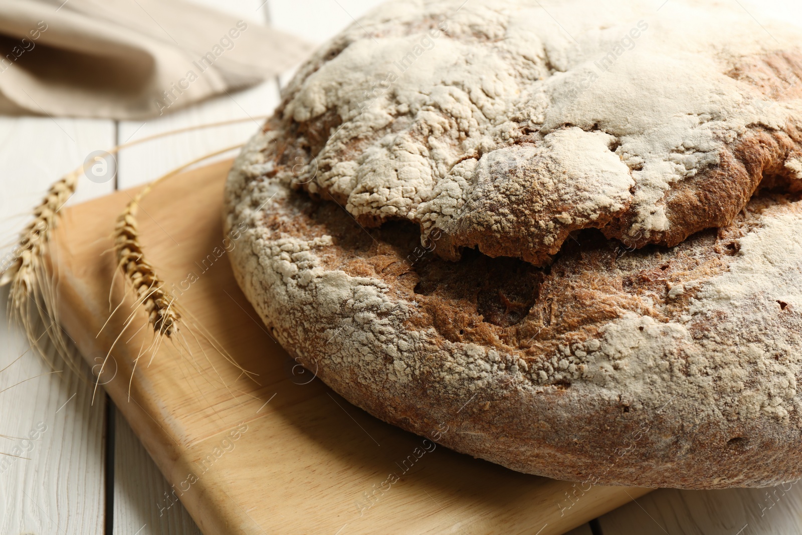 Photo of Loaf of delicious fresh bread on white wooden table, closeup