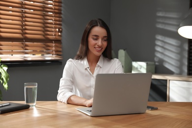 Young woman using laptop for search at wooden table in office Photo of Young woman using laptop for search at wooden table in office