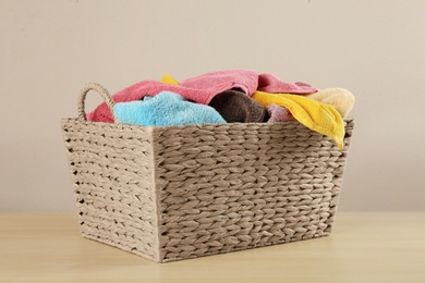 Wicker laundry basket with towels on wooden table Photo of Wicker laundry basket with towels on wooden table