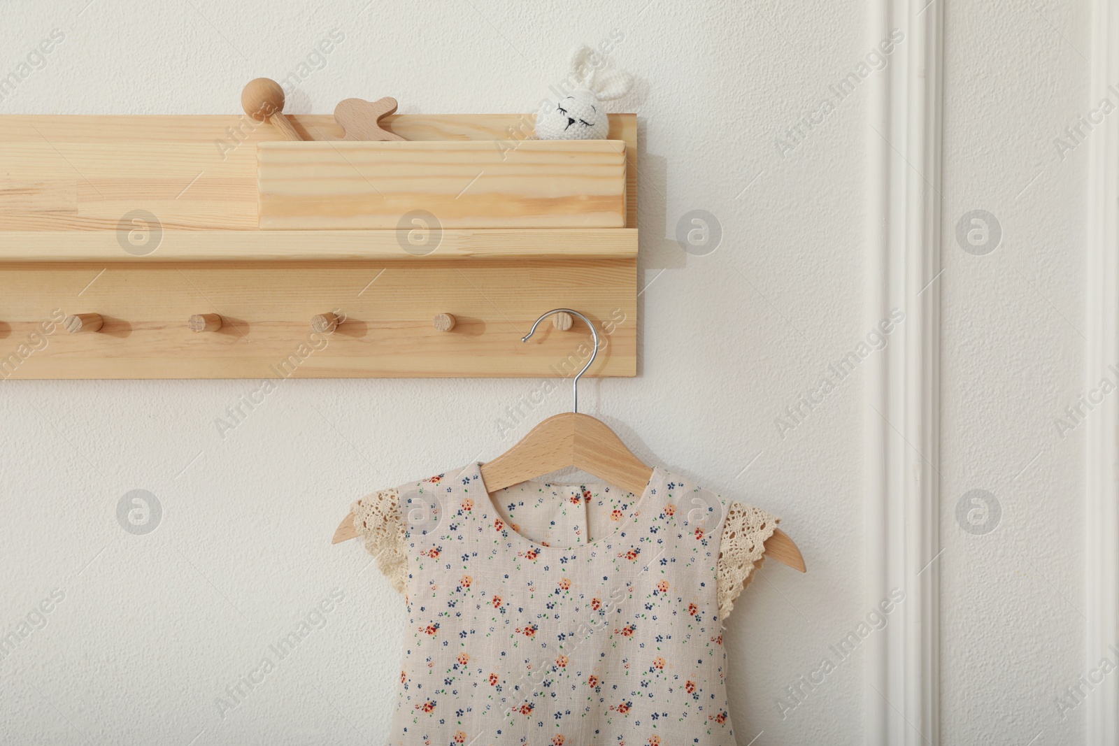 Wooden rack with cute dress in child room. Interior design Photo of Wooden rack with cute dress in child room. Interior design