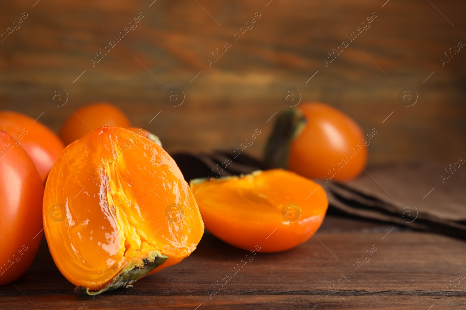 Delicious fresh persimmons on brown wooden table, closeup Photo of Delicious fresh persimmons on brown wooden table, closeup