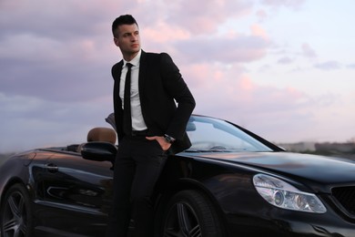 Handsome businessman near luxury convertible car outdoors Photo of Handsome businessman near luxury convertible car outdoors