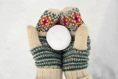 Woman in knitted mittens holding snowball outdoors, top view Photo of Woman in knitted mittens holding snowball outdoors, top view