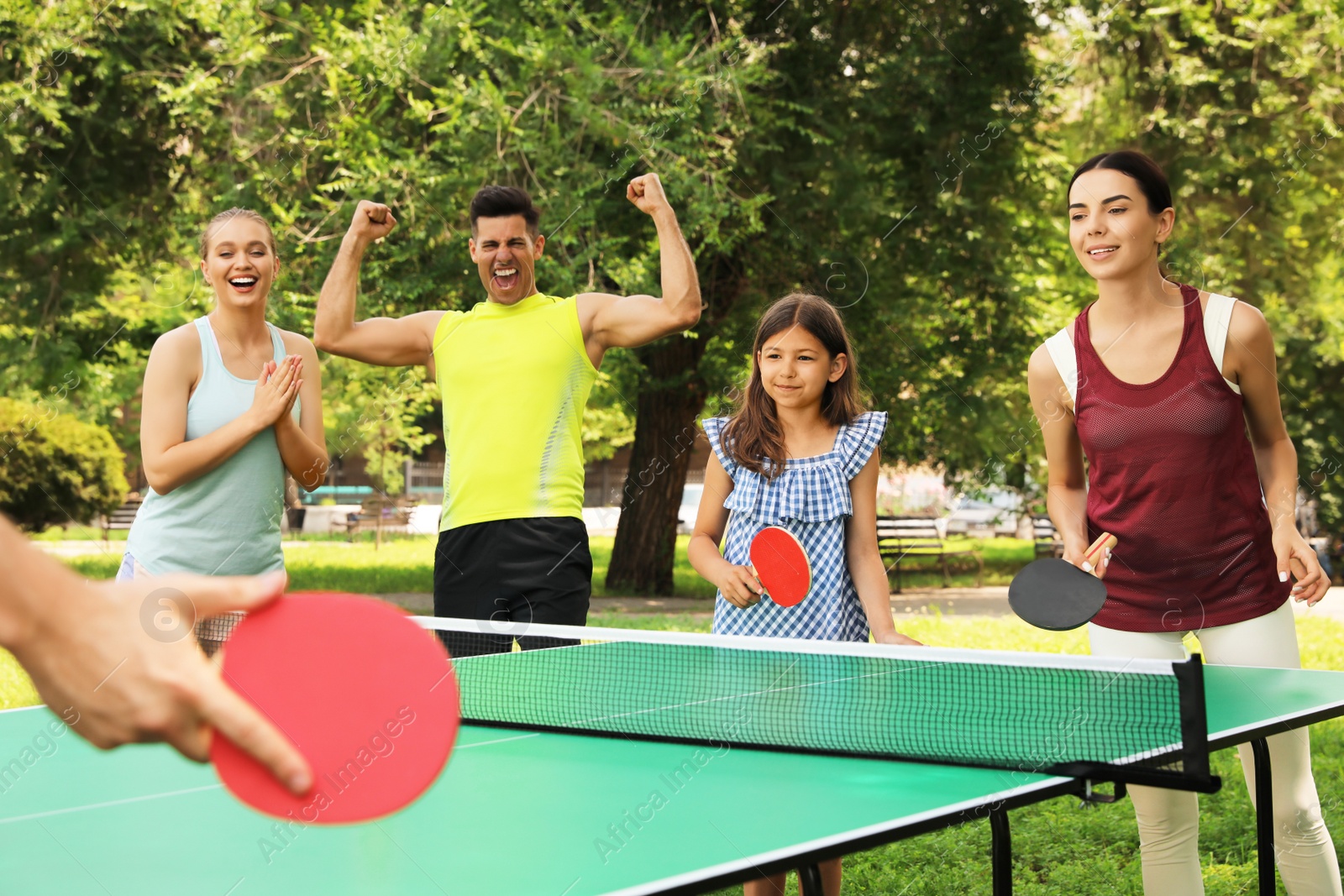 Photo of Happy family playing ping pong in park