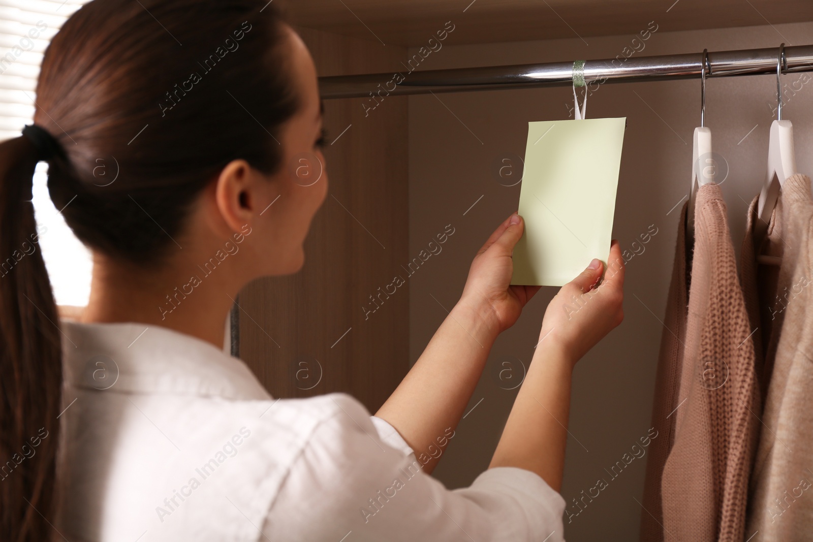 Young woman holding scented sachet in wardrobe Photo of Young woman holding scented sachet in wardrobe