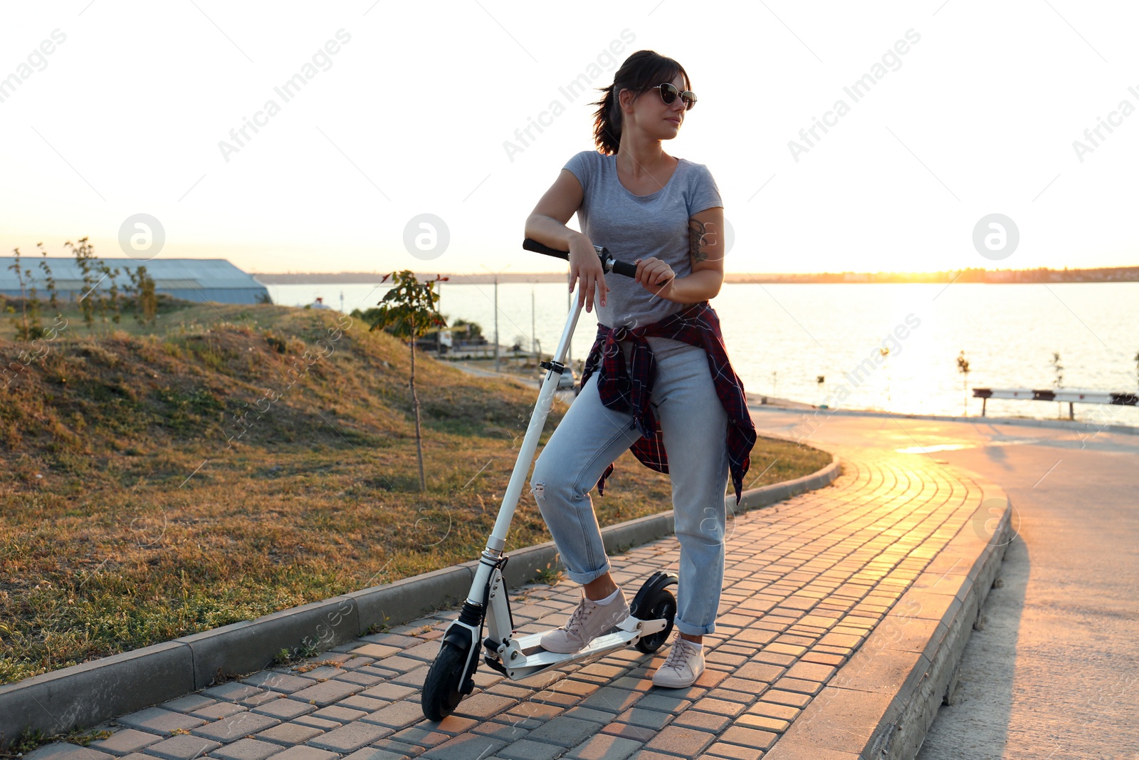 Young woman with kick scooter on city street Photo of Young woman with kick scooter on city street