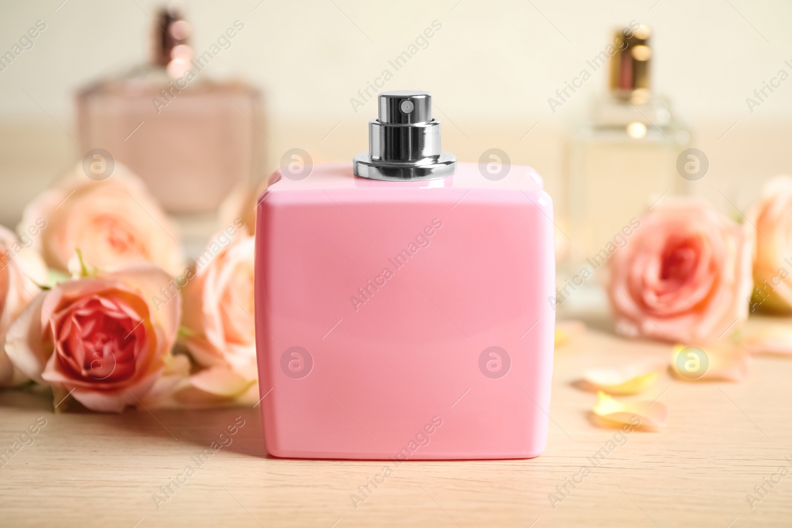 Bottles of perfume and beautiful flowers on wooden table Photo of Bottles of perfume and beautiful flowers on wooden table