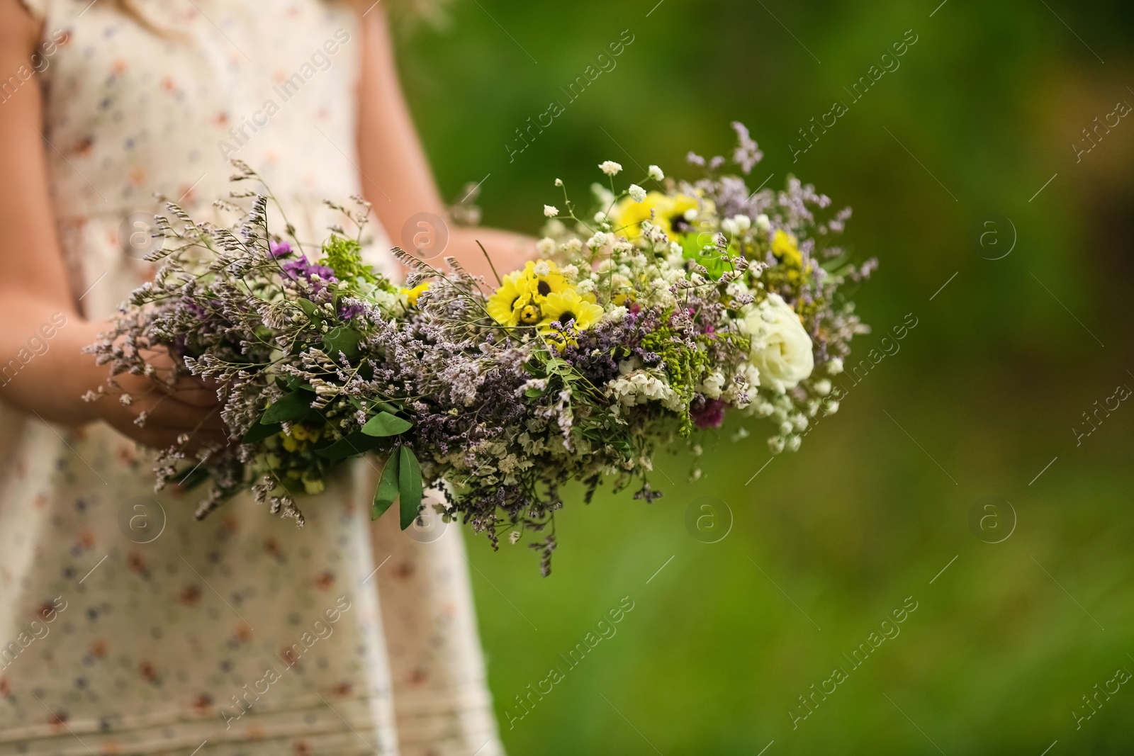 Cute little girl holding wreath made of beautiful flowers outdoors, closeup Photo of Cute little girl holding wreath made of beautiful flowers outdoors, closeup
