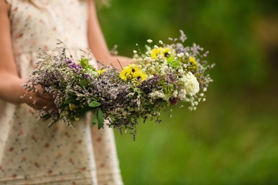 Cute little girl holding wreath made of beautiful flowers outdoors, closeup Photo of Cute little girl holding wreath made of beautiful flowers outdoors, closeup