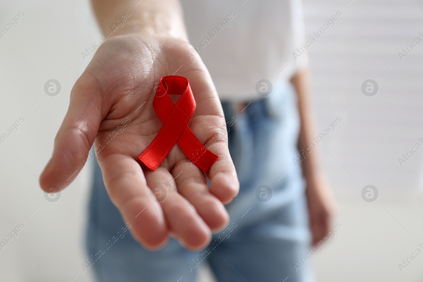 Woman holding red awareness ribbon on light background, closeup with space for text. World AIDS disease day Photo of Woman holding red awareness ribbon on light background, closeup with space for text. World AIDS disease day