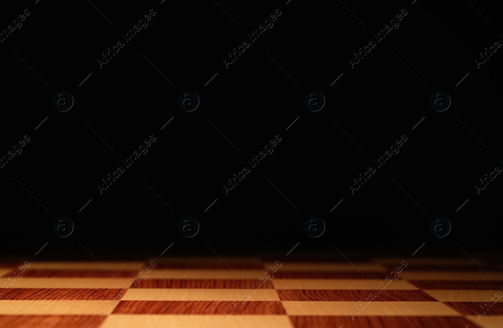 Photo of Checkered chessboard on dark background, closeup. Space for text