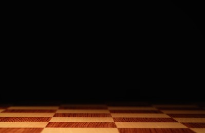 Checkered chessboard on dark background, closeup. Space for text Photo of Checkered chessboard on dark background, closeup. Space for text