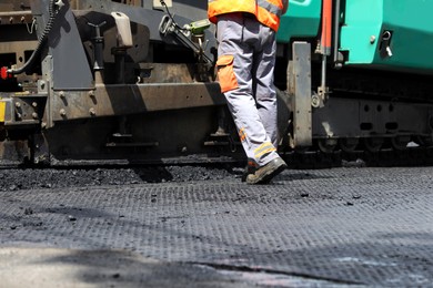 Worker laying new asphalt with paver, closeup. Road repair Photo of Worker laying new asphalt with paver, closeup. Road repair