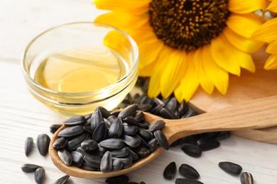 Sunflower seeds and oil on white wooden table, closeup Photo of Sunflower seeds and oil on white wooden table, closeup