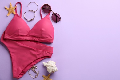 Beautiful pink bikini and beach accessories on lilac background, flat lay. Space for text Photo of Beautiful pink bikini and beach accessories on lilac background, flat lay. Space for text