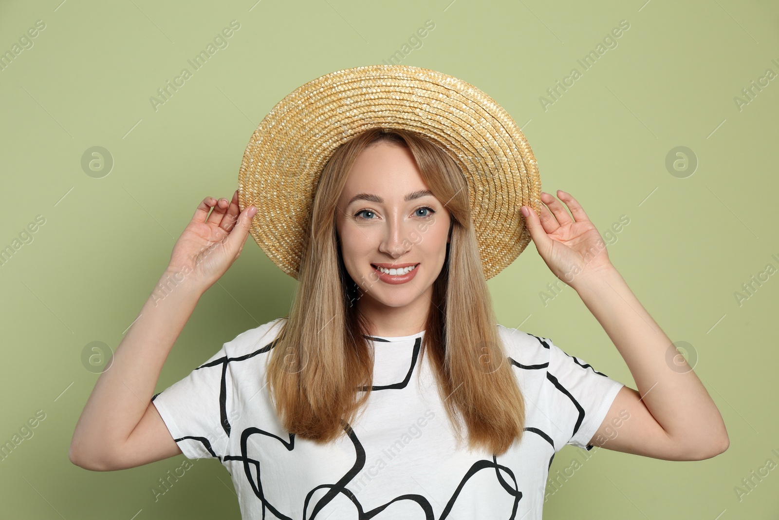 Beautiful young woman wearing straw hat on light green background. Stylish headdress Photo of Beautiful young woman wearing straw hat on light green background. Stylish headdress