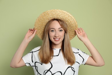 Beautiful young woman wearing straw hat on light green background. Stylish headdress Photo of Beautiful young woman wearing straw hat on light green background. Stylish headdress