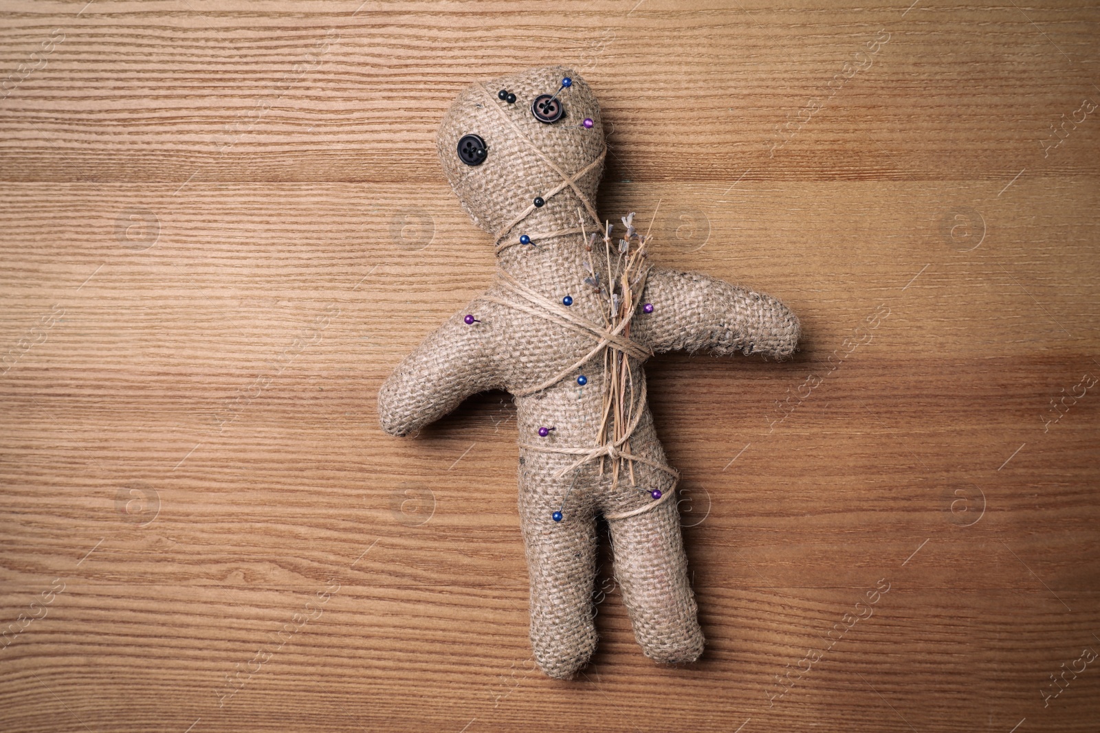 Voodoo doll pierced with pins on wooden table, top view Photo of Voodoo doll pierced with pins on wooden table, top view