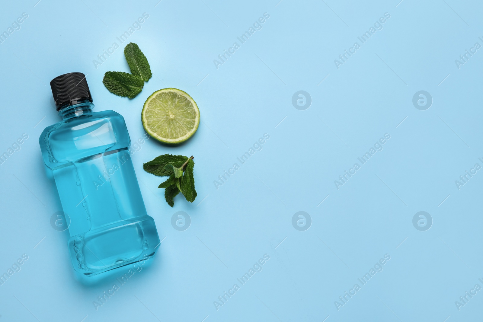 Mouthwash, mint and lime on light blue background, flat lay. Space for text Photo of Mouthwash, mint and lime on light blue background, flat lay. Space for text