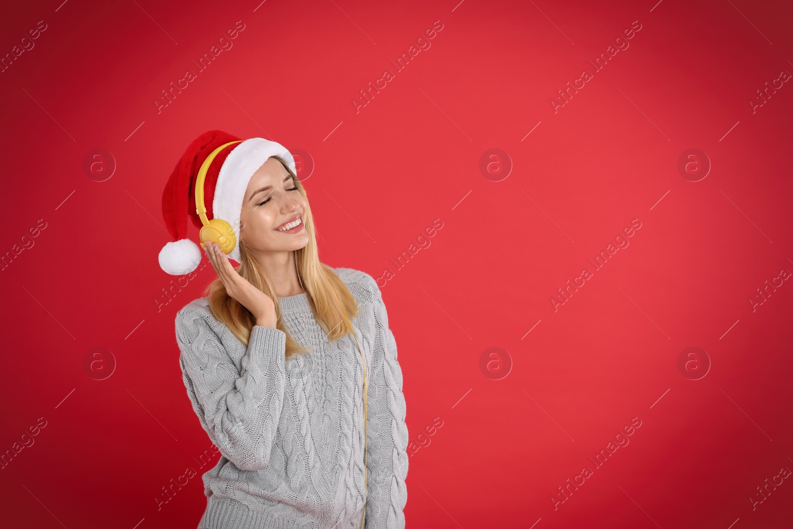 Happy woman with headphones on red background, space for text. Christmas music Photo of Happy woman with headphones on red background, space for text. Christmas music
