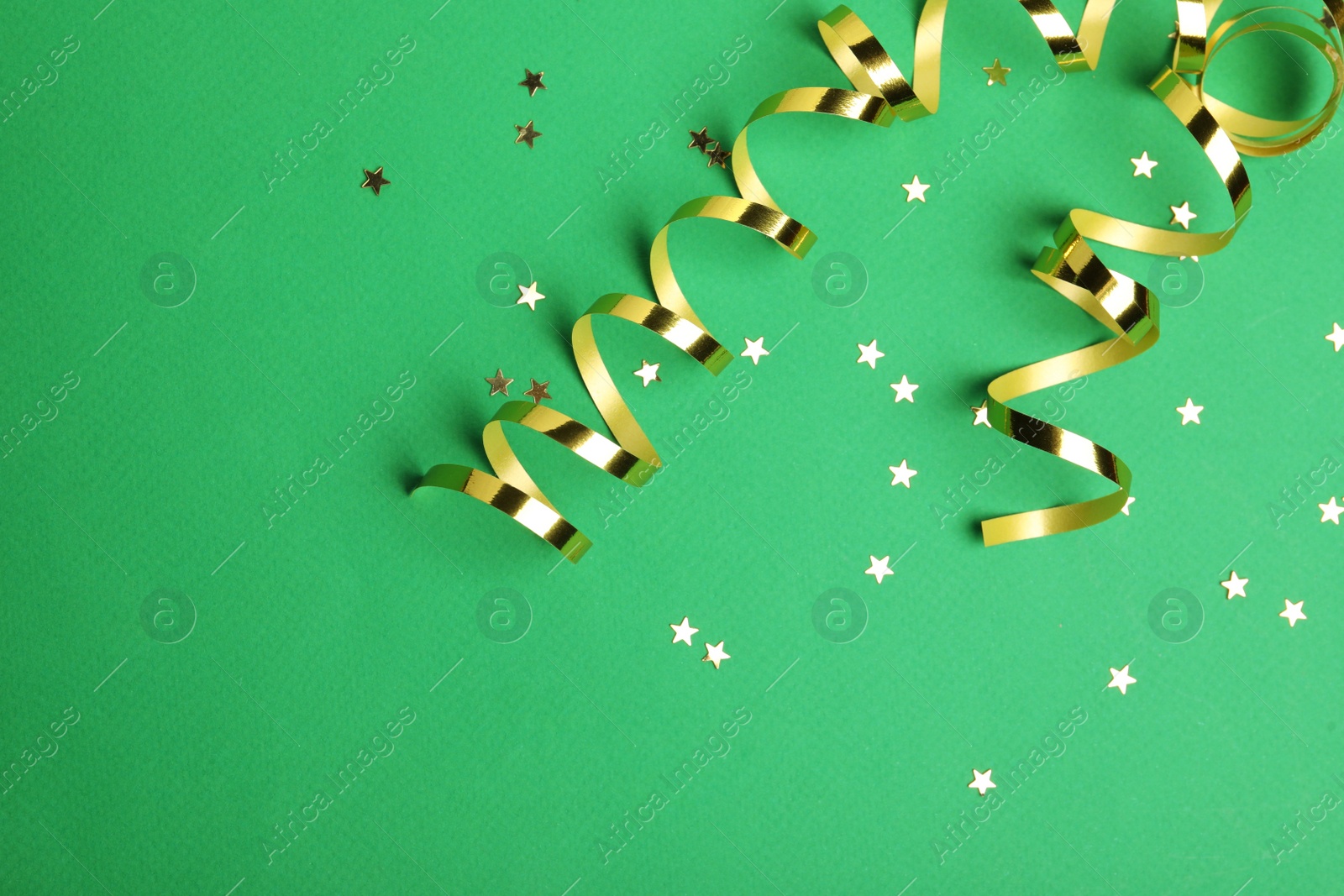 Shiny golden serpentine streamers and confetti on green background, flat lay. Space for text Photo of Shiny golden serpentine streamers and confetti on green background, flat lay. Space for text