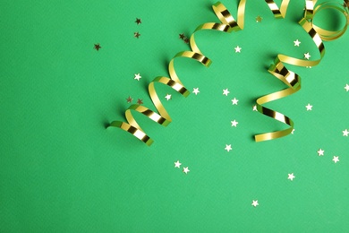 Shiny golden serpentine streamers and confetti on green background, flat lay. Space for text Photo of Shiny golden serpentine streamers and confetti on green background, flat lay. Space for text