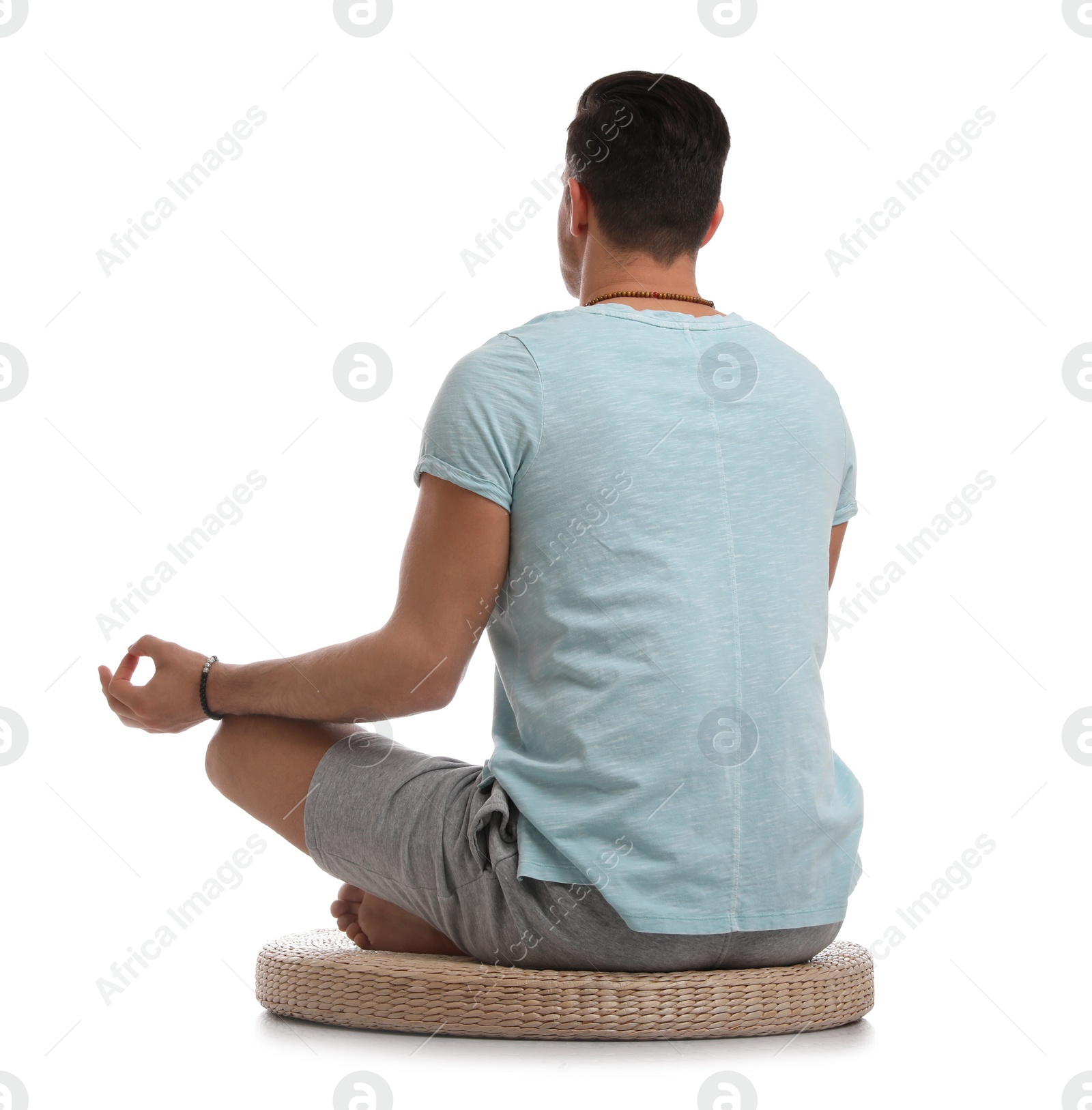 Man meditating on white background, back view Photo of Man meditating on white background, back view