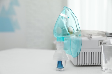 Modern nebulizer with face mask and medicine on white table indoors, space for text. Inhalation equipment Photo of Modern nebulizer with face mask and medicine on white table indoors, space for text. Inhalation equipment