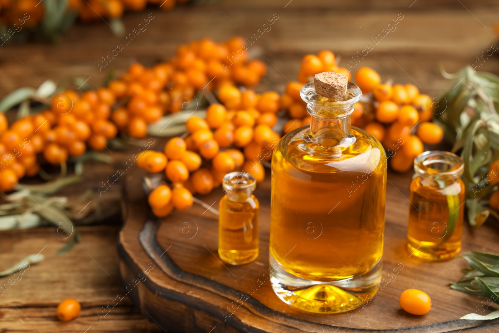 Photo of Natural sea buckthorn oil and fresh berries on wooden table