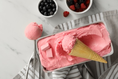 Delicious ice cream in container and wafer cone on white marble table, flat lay Photo of Delicious ice cream in container and wafer cone on white marble table, flat lay