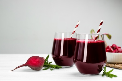 Fresh beet juice and raw vegetable on white wooden table Photo of Fresh beet juice and raw vegetable on white wooden table