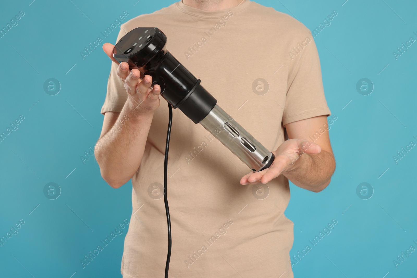 Man holding sous vide cooker on light blue background. closeup Photo of Man holding sous vide cooker on light blue background. closeup