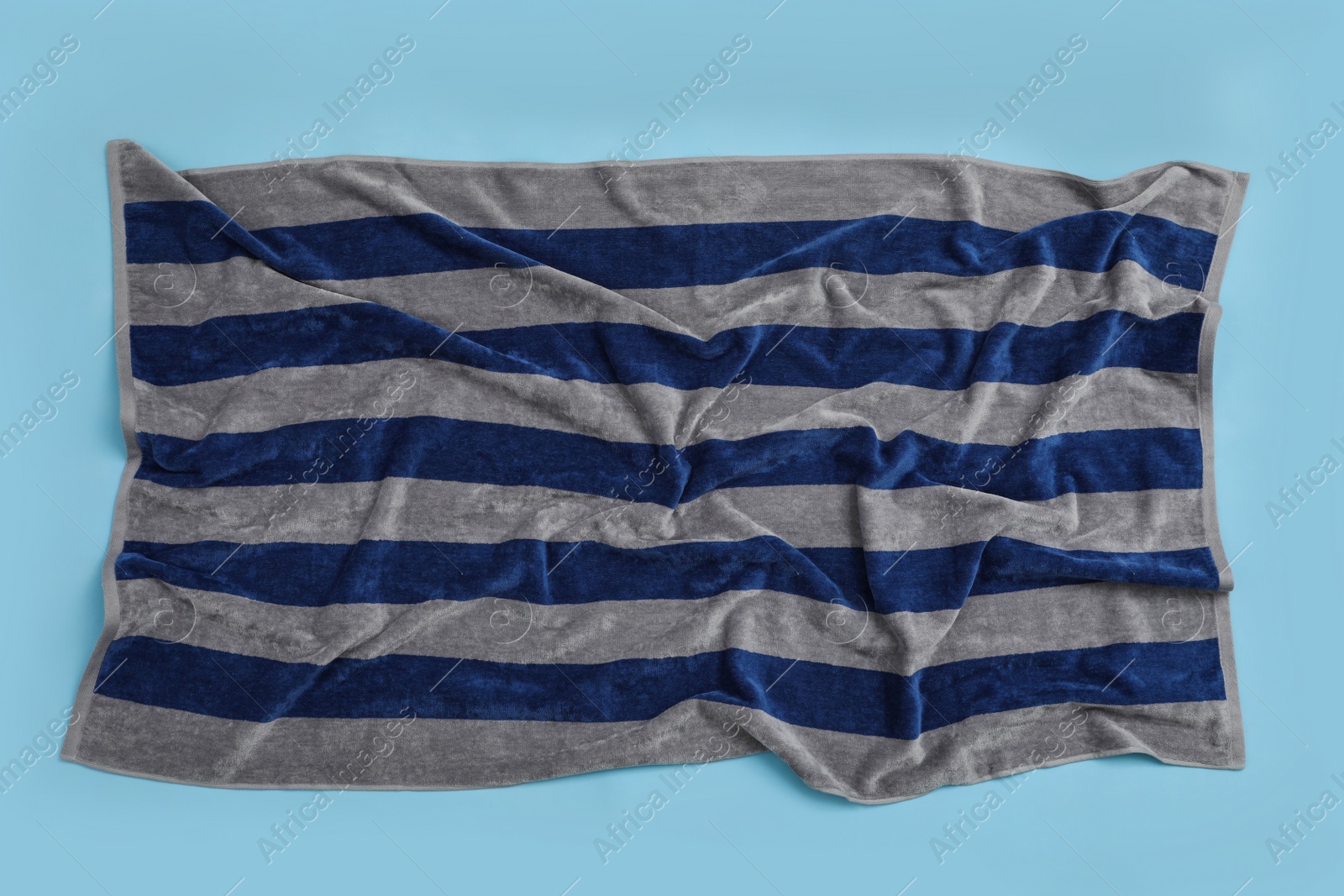 Crumpled striped beach towel on light blue background, top view Photo of Crumpled striped beach towel on light blue background, top view
