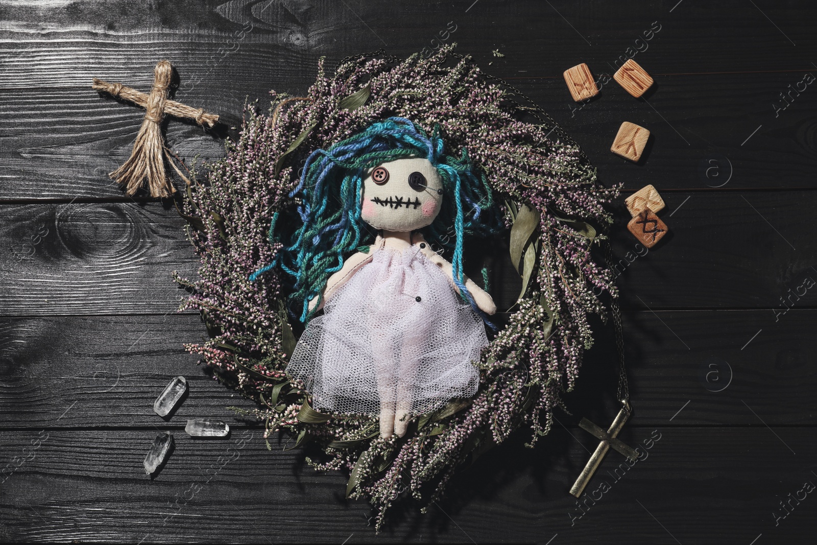 Female voodoo doll with pins surrounded by ceremonial items on black wooden background, flat lay Photo of Female voodoo doll with pins surrounded by ceremonial items on black wooden background, flat lay