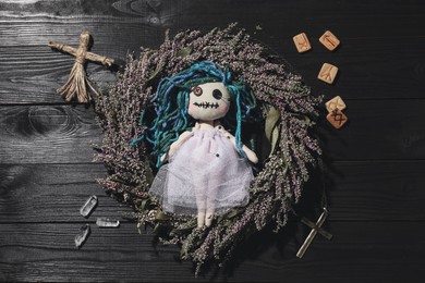 Female voodoo doll with pins surrounded by ceremonial items on black wooden background, flat lay Photo of Female voodoo doll with pins surrounded by ceremonial items on black wooden background, flat lay