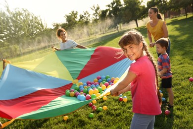 Group of children and teachers playing with rainbow playground parachute on green grass. Summer camp activity Photo of Group of children and teachers playing with rainbow playground parachute on green grass. Summer camp activity