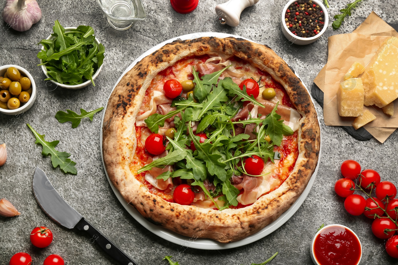 Tasty pizza with meat and arugula on grey table, flat lay Photo of Tasty pizza with meat and arugula on grey table, flat lay
