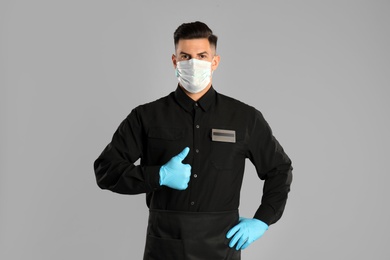 Waiter wearing medical face mask on light grey background Photo of Waiter wearing medical face mask on light grey background
