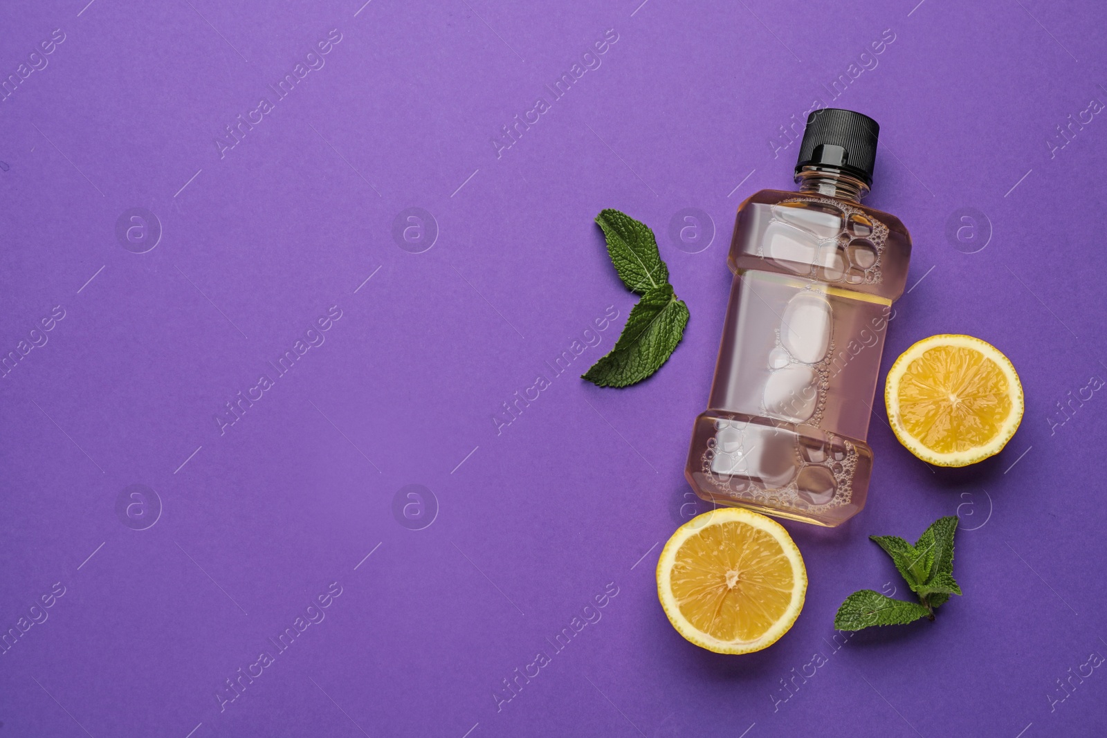 Mouthwash, fresh mint and lemon on purple background, flat lay. Space for text Photo of Mouthwash, fresh mint and lemon on purple background, flat lay. Space for text
